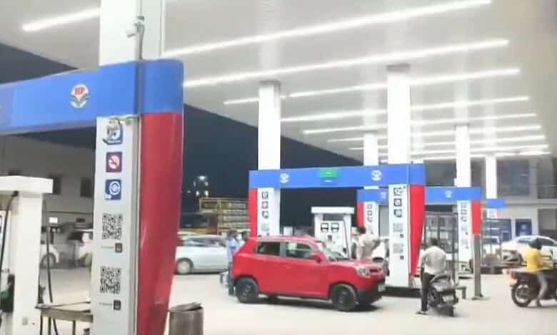 Fuel station with red car and fuel pumps in Hyderabad, where a man alleges fuel meter tampering after fil.