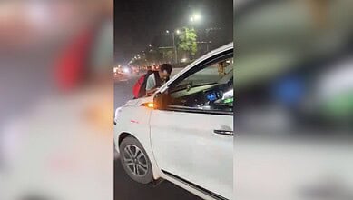 Man being dragged on car bonnet during dispute in Hyderabad at night.
