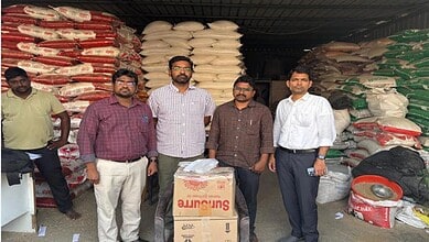 Vendors standing in front of stacked rice and grain bags at wholesale market in Hyderabad.