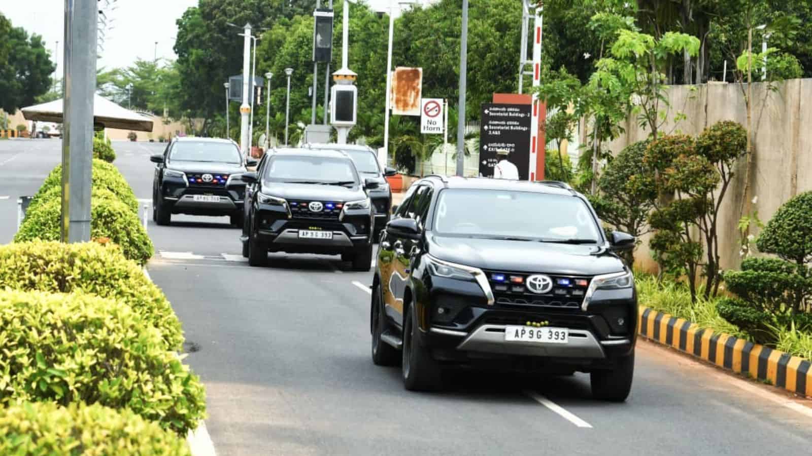 Traffic congestion on a busy urban road with multiple cars and greenery.