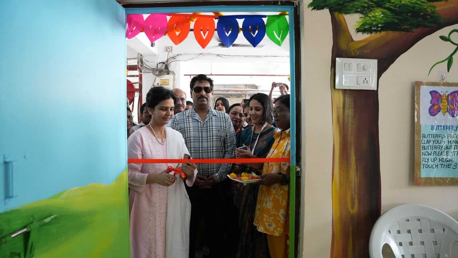 Image shows a woman cutting a ribbon during an event at the Siasat Daily office, with attendees and colourful decorations in the background.