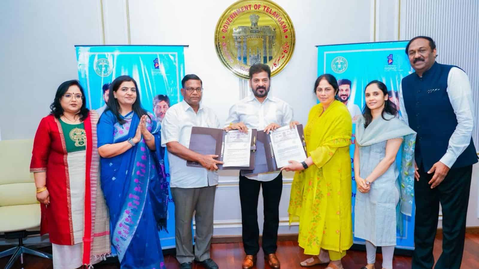 Government officials and women representatives participate in signing documents at the Telangana governme.