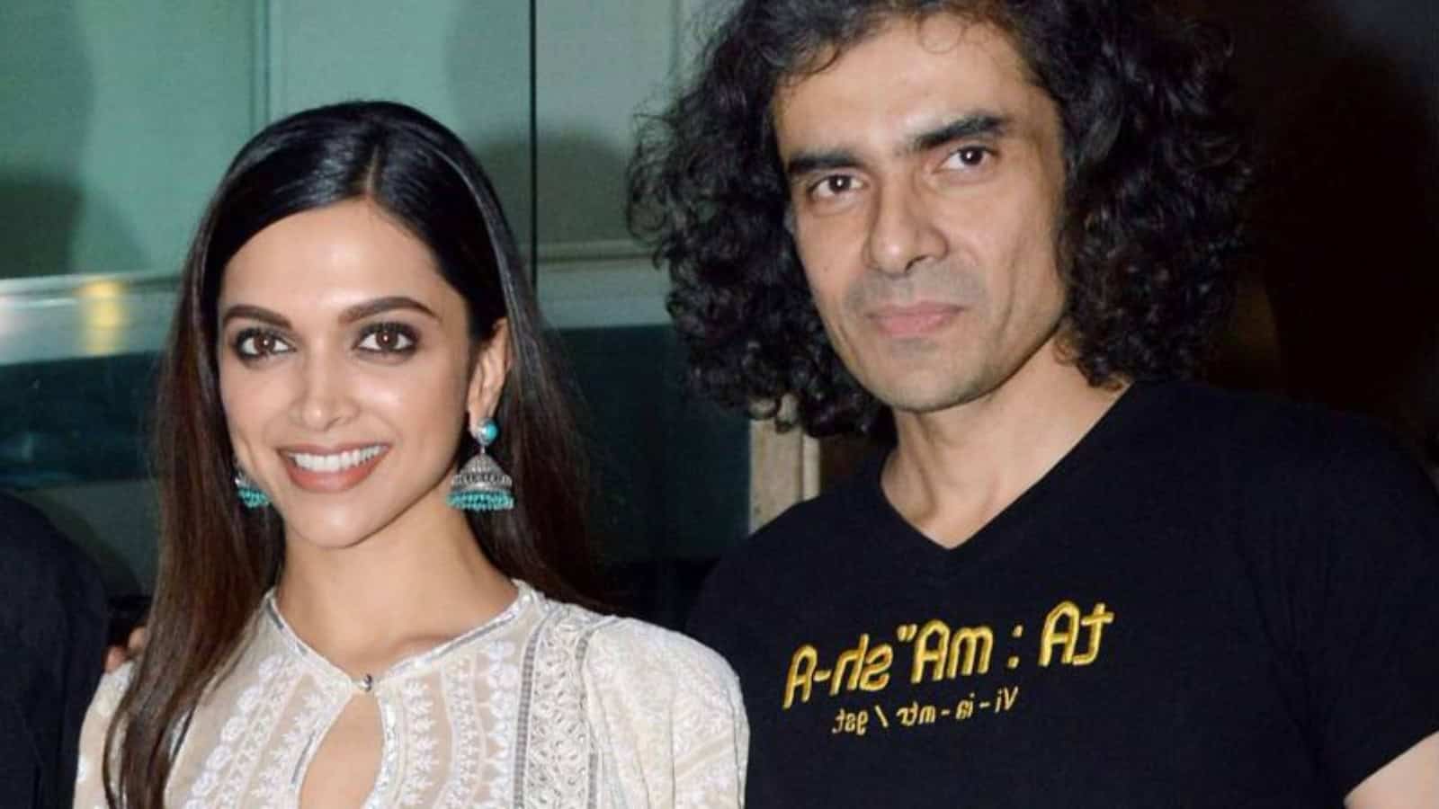 A woman smiling in traditional attire with a man wearing a black T-shirt featuring scientific text.