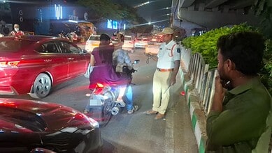 Traffic police stop vehicle on busy Hyderabad street at night.