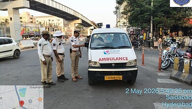 Police officers inspecting an ambulance at a busy intersection in Hyderabad.