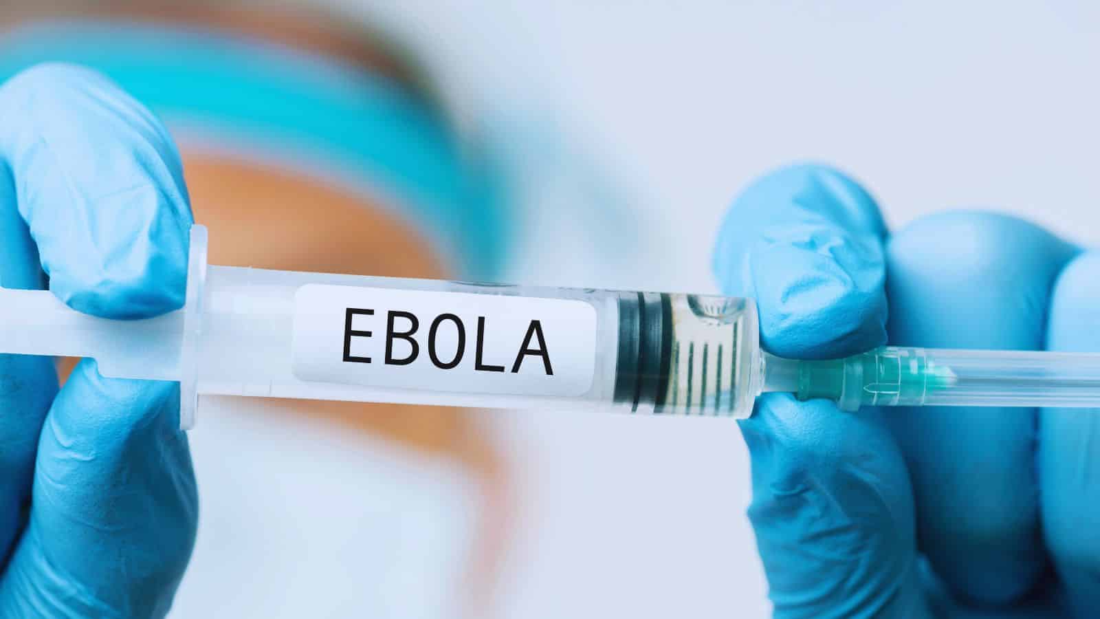 A healthcare professional in blue gloves holding a syringe labeled 'Ebola' vaccine, highlighting efforts to combat Ebola outbreaks.