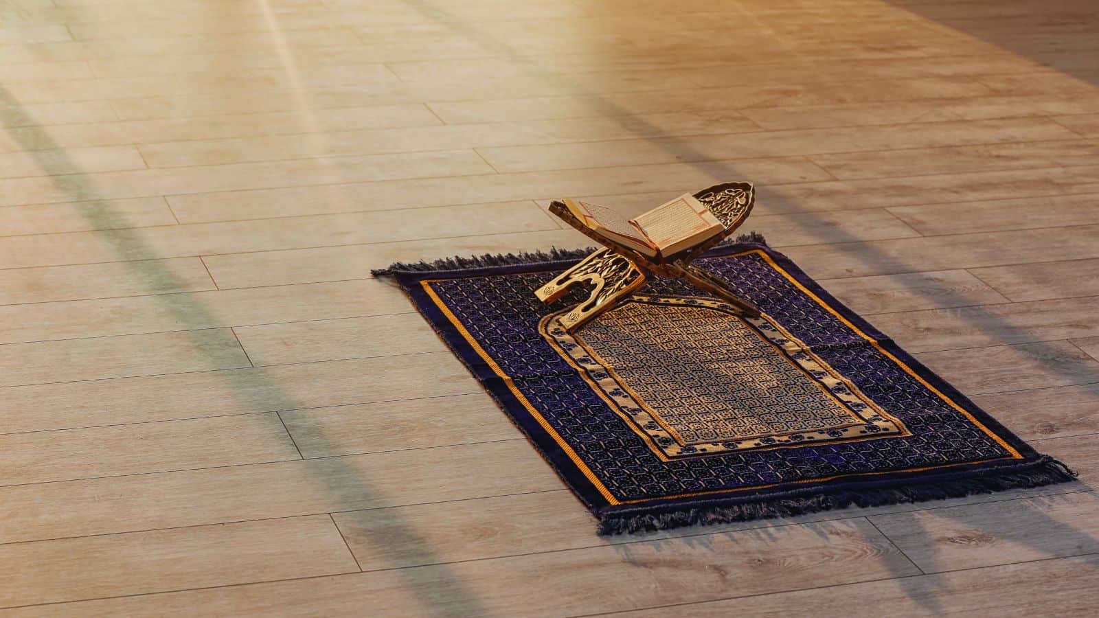 Prayer rug with Quran and prayer beads placed on wooden floor, symbolising Islamic worship and spirituali.