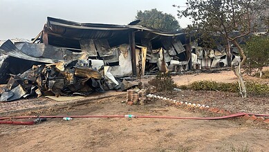 Burned and damaged structures after fire incident at a building site. Charred remains and debris visible.