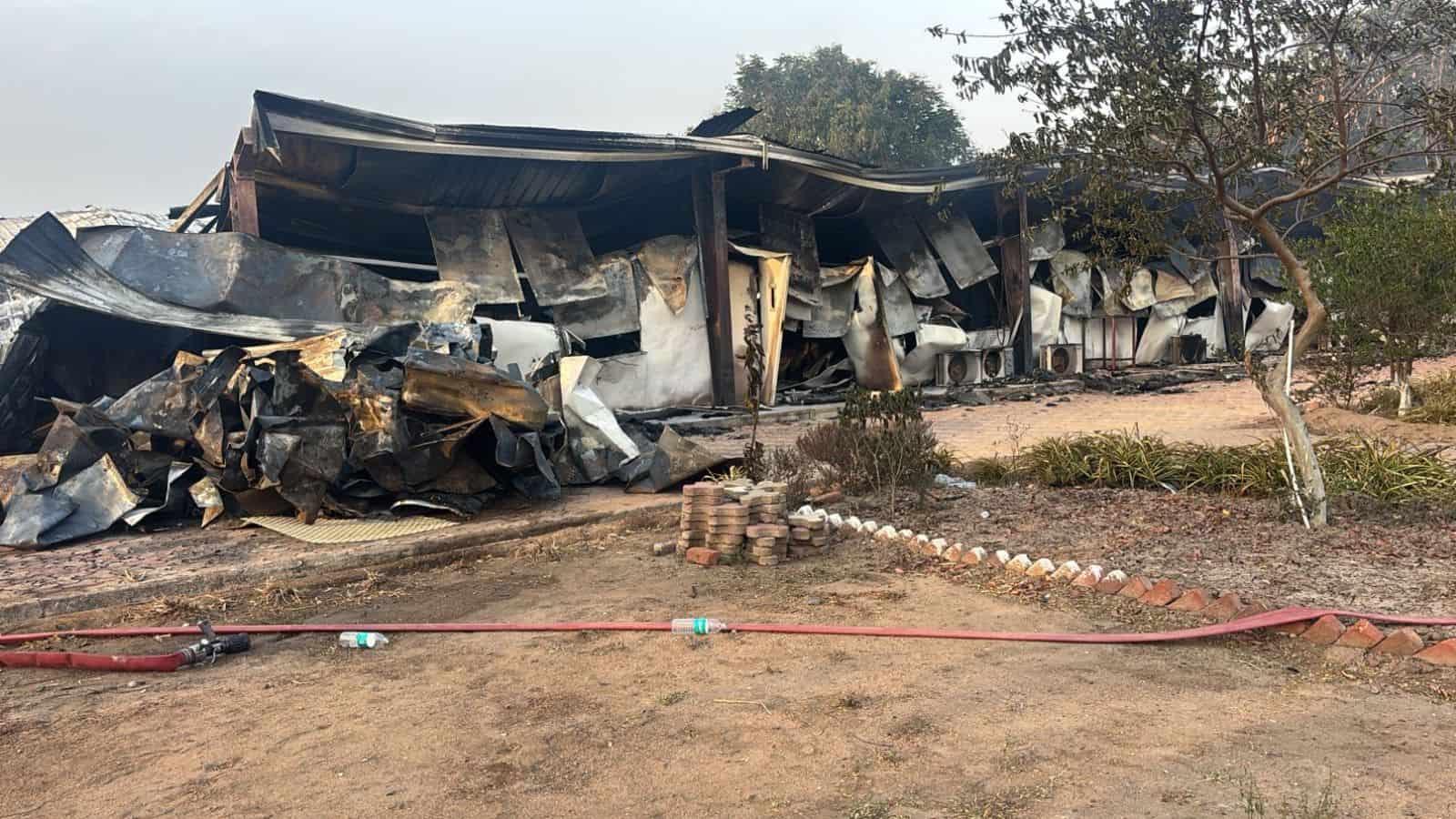 Burned and damaged structures after fire incident at a building site. Charred remains and debris visible.