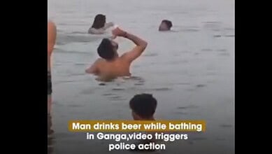 Man drinking beer while bathing in Ganga river, video captures police action in India.