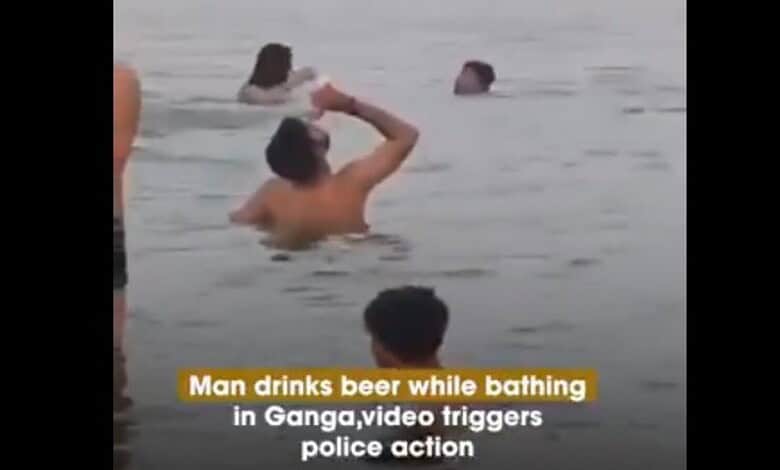 Man drinking beer while bathing in Ganga river, video captures police action in India.
