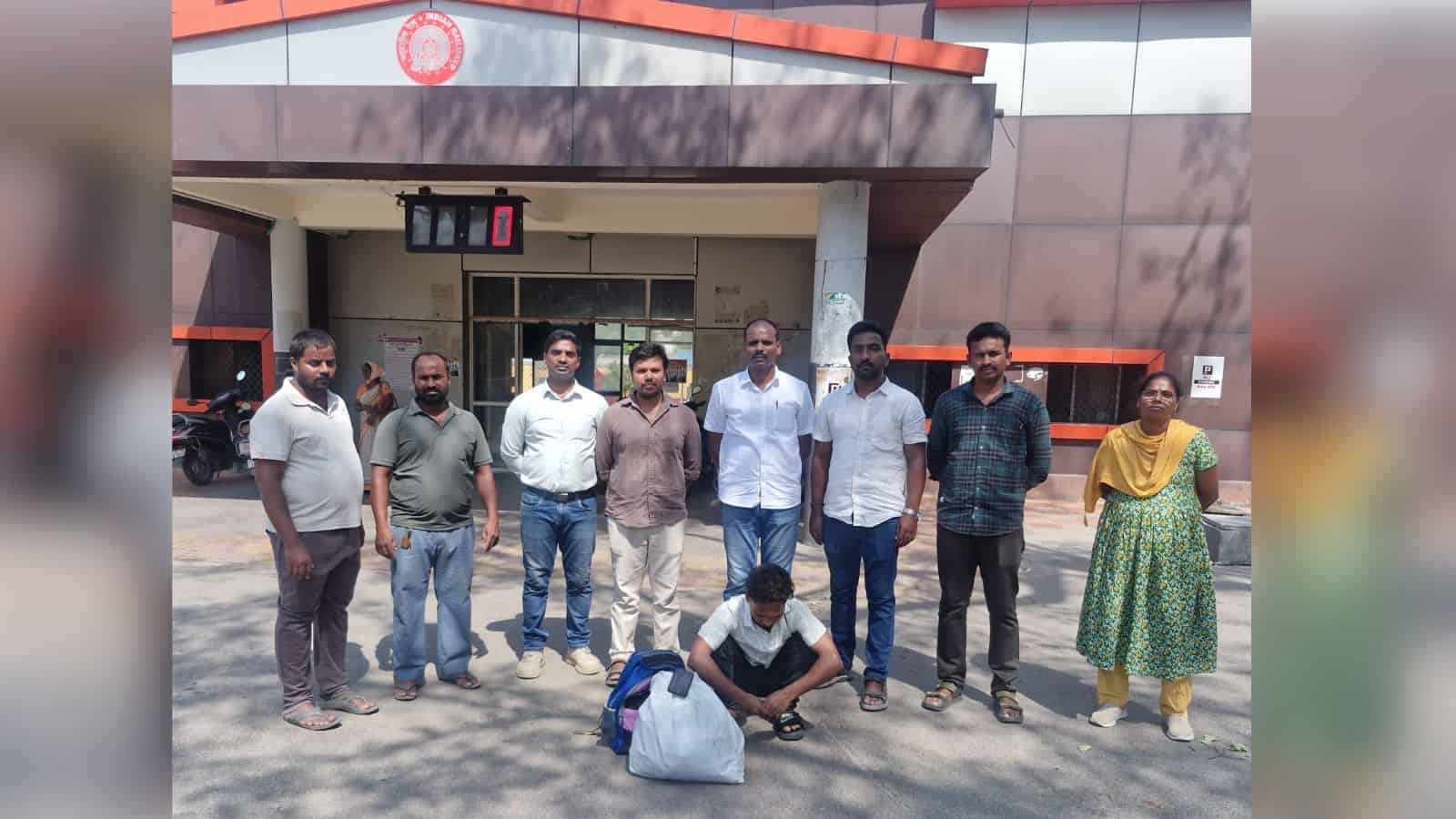 The Siasat Daily office building with a group of nine diverse individuals standing outside, some smiling,.