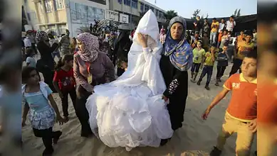Women and children participating in a cultural celebration outdoors.