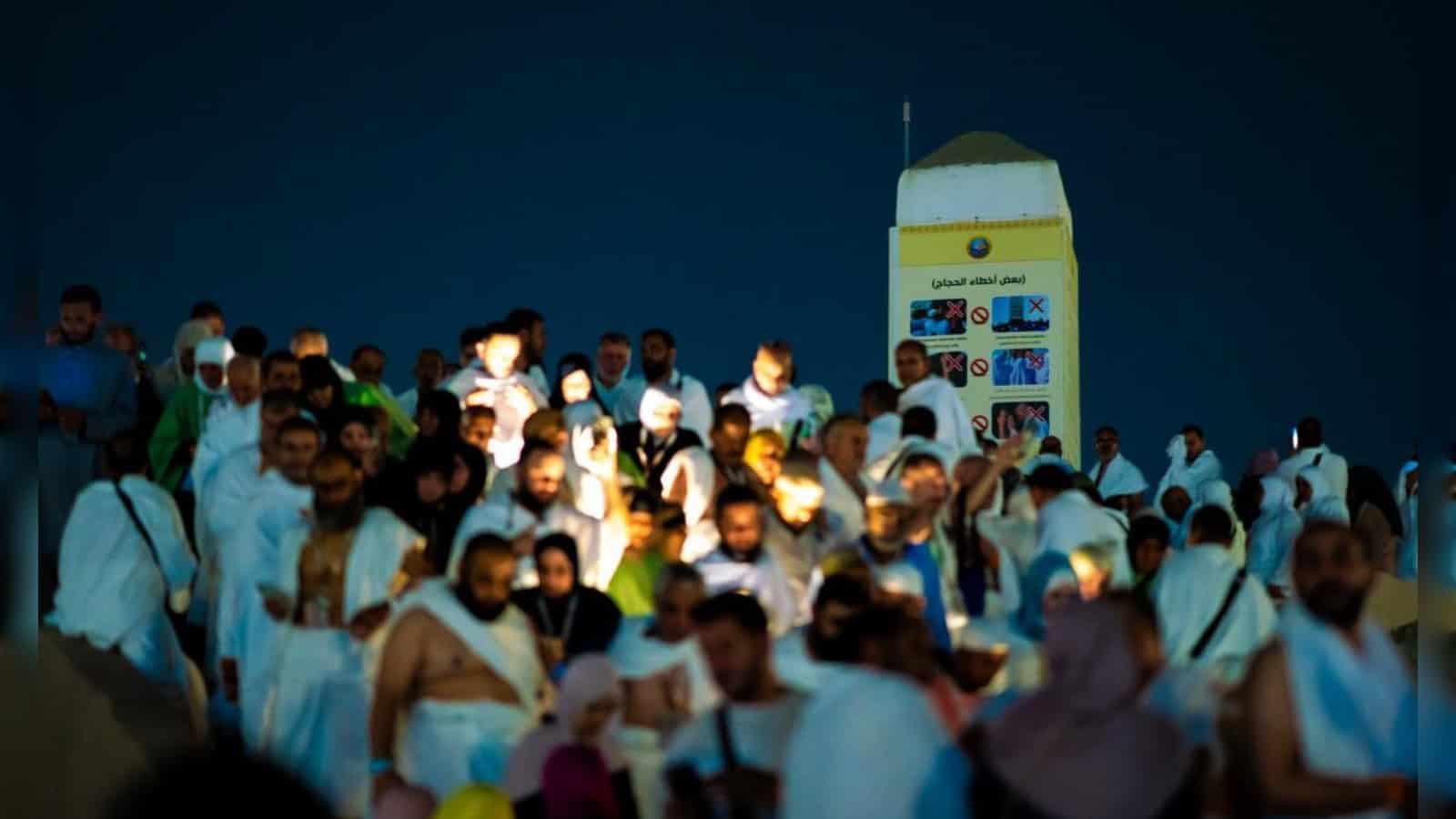 Crowd of men and women dressed in white attending a religious gathering outdoors at night.