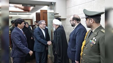 A group of officials, including a military officer and government representatives, greeting a distinguish.