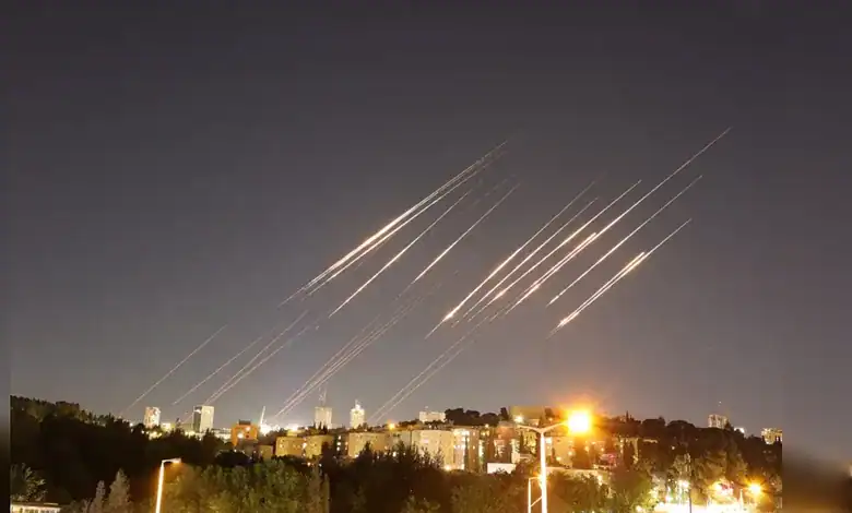 Multiple missiles streak across the night sky above a cityscape, illuminated by bright city lights and ex.
