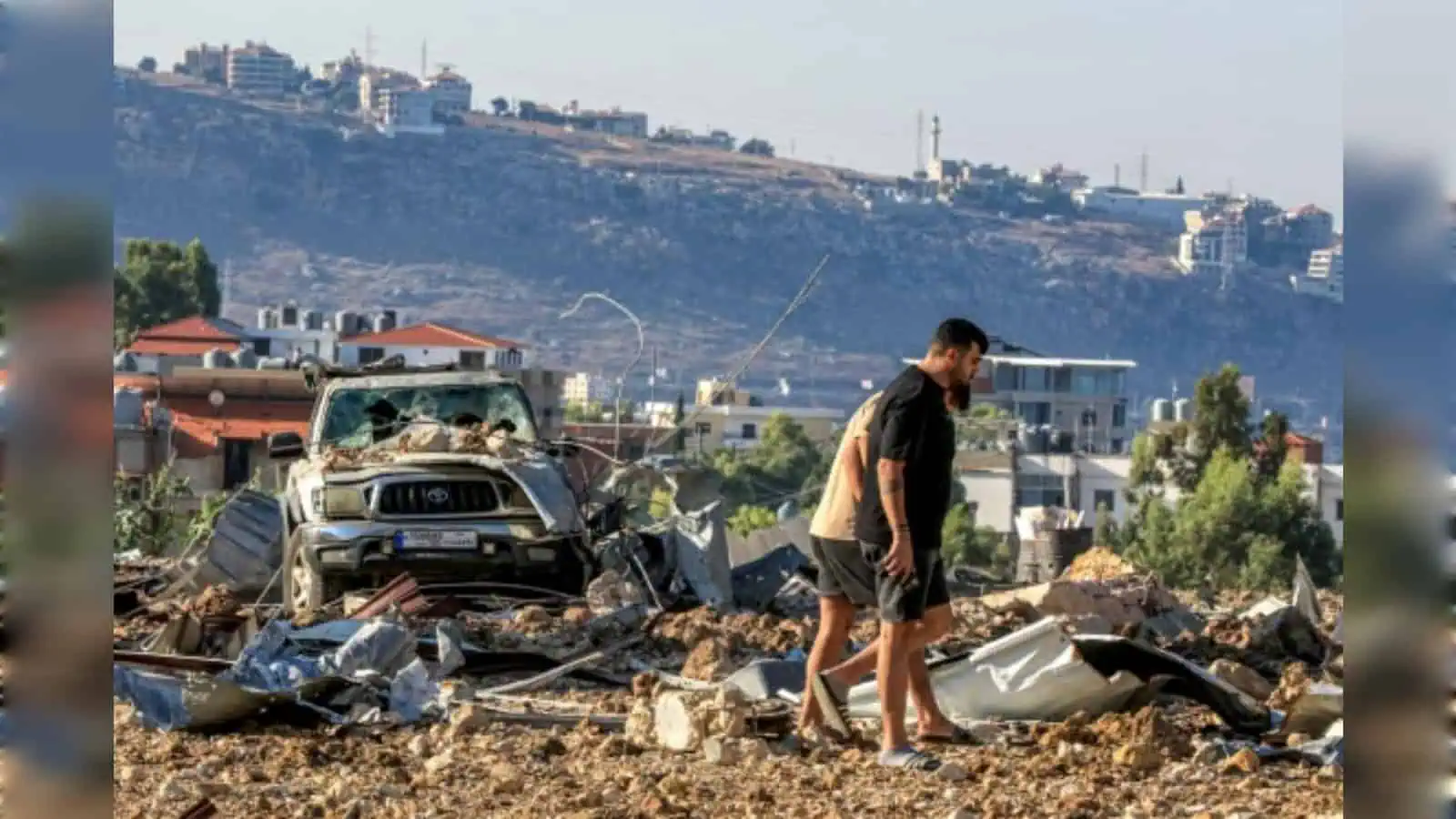 Explosion aftermath in urban area with debris and damaged vehicles.