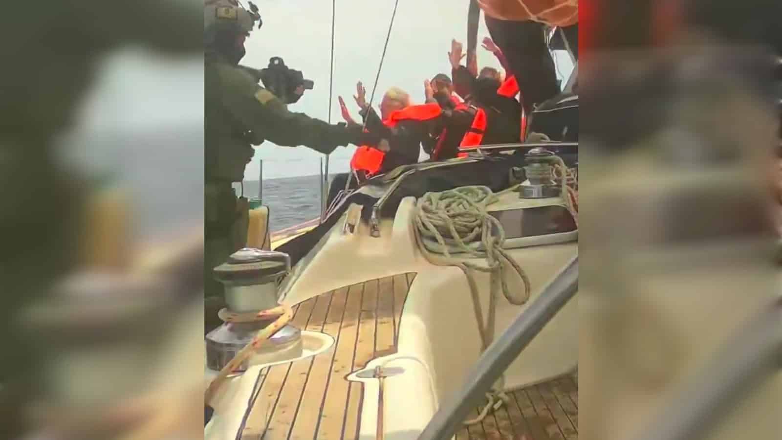 Yacht crew helping passengers with safety gear on a boat at sea.