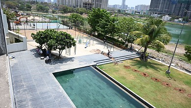 Swimming pool and green garden area in a modern residential complex with city skyline in the background.