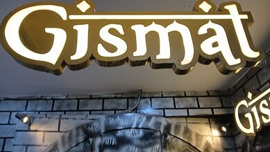 Illuminated Gismat restaurant sign at night with bright lighting and modern design.
