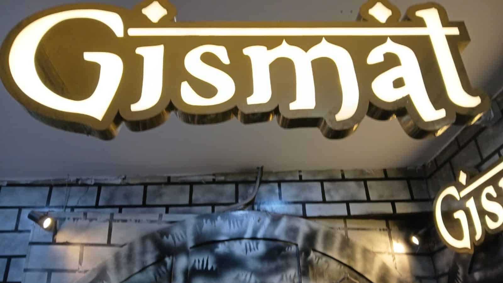 Illuminated Gismat restaurant sign at night with bright lighting and modern design.