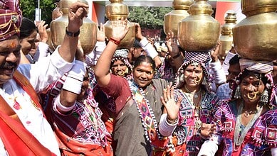 Vibrant group of women in traditional attire celebrating with brass pots during a cultural festival in In.