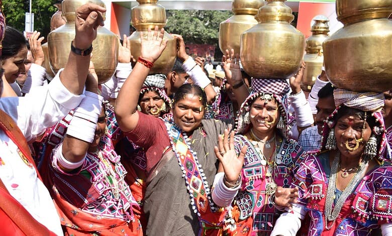 Vibrant group of women in traditional attire celebrating with brass pots during a cultural festival in In.