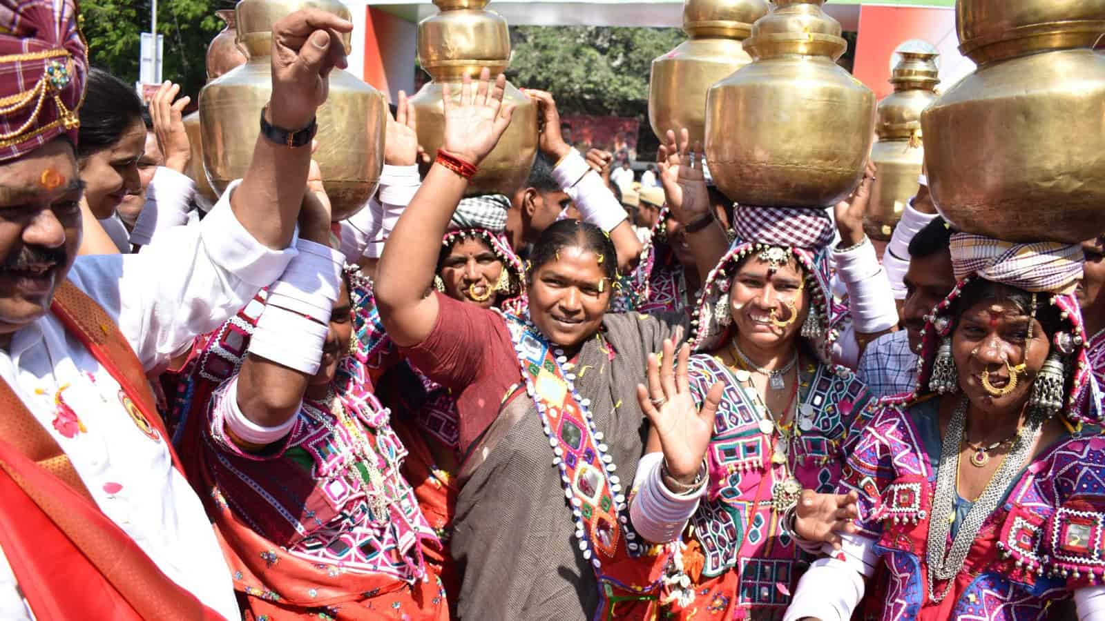 Vibrant group of women in traditional attire celebrating with brass pots during a cultural festival in In.
