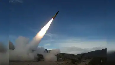 Missile launch during military exercise in desert landscape.