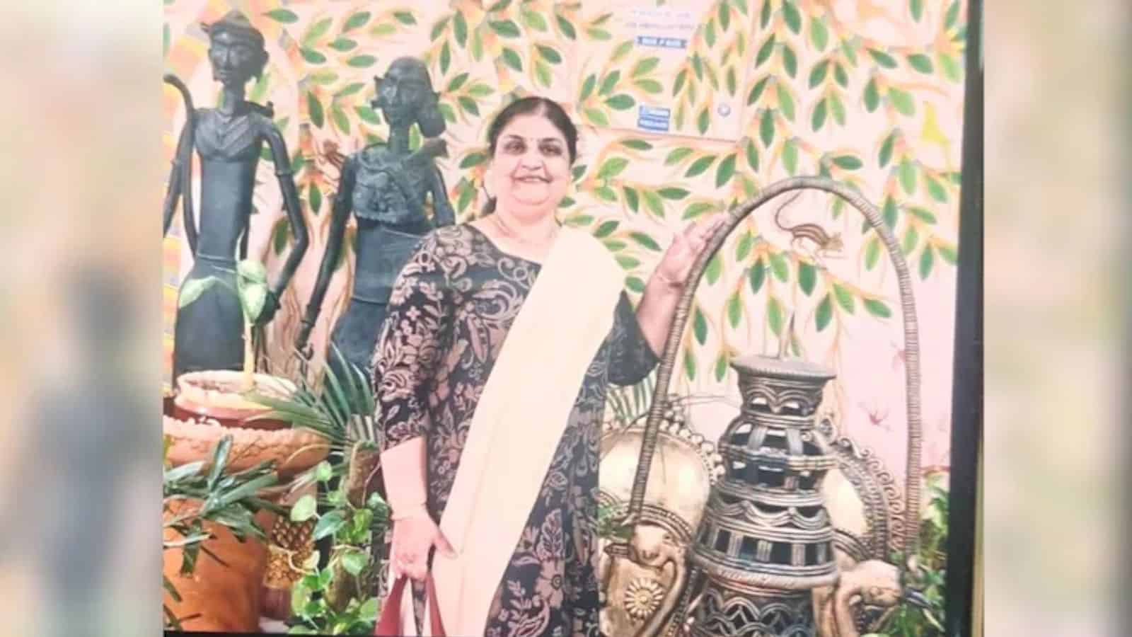 Traditional Indian woman with cultural artifacts and greenery background.