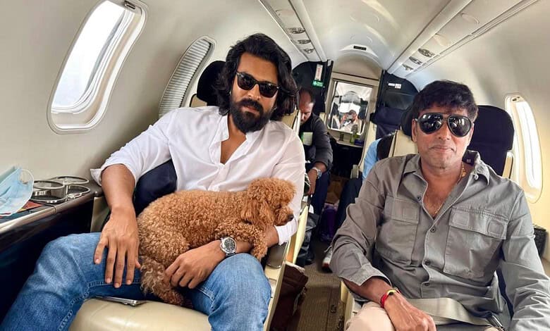 Ram Charan seated on a private jet with a dog, enjoying a travel moment.