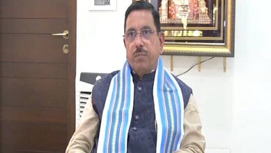 A man wearing glasses and a blue and white striped scarf sitting in an office setting.