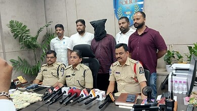 A police officer seated at a desk with five men standing behind, in a press conference setting.