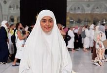 Woman in white hijab praying at Masjid al-Haram during Hajj pilgrimage, Mecca, Saudi Arabia.