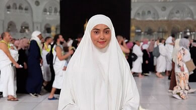 Woman in white hijab praying at Masjid al-Haram during Hajj pilgrimage, Mecca, Saudi Arabia.