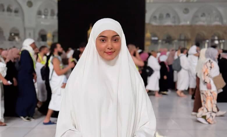 Woman in white hijab praying at Masjid al-Haram during Hajj pilgrimage, Mecca, Saudi Arabia.