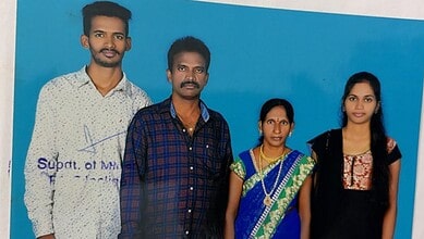 A man and woman standing with two young women against a blue background, smiling and dressed in casual at.