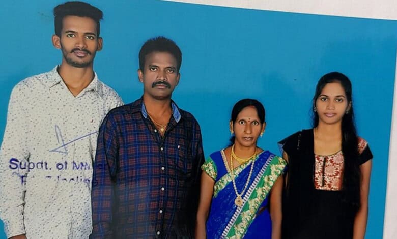 A man and woman standing with two young women against a blue background, smiling and dressed in casual at.