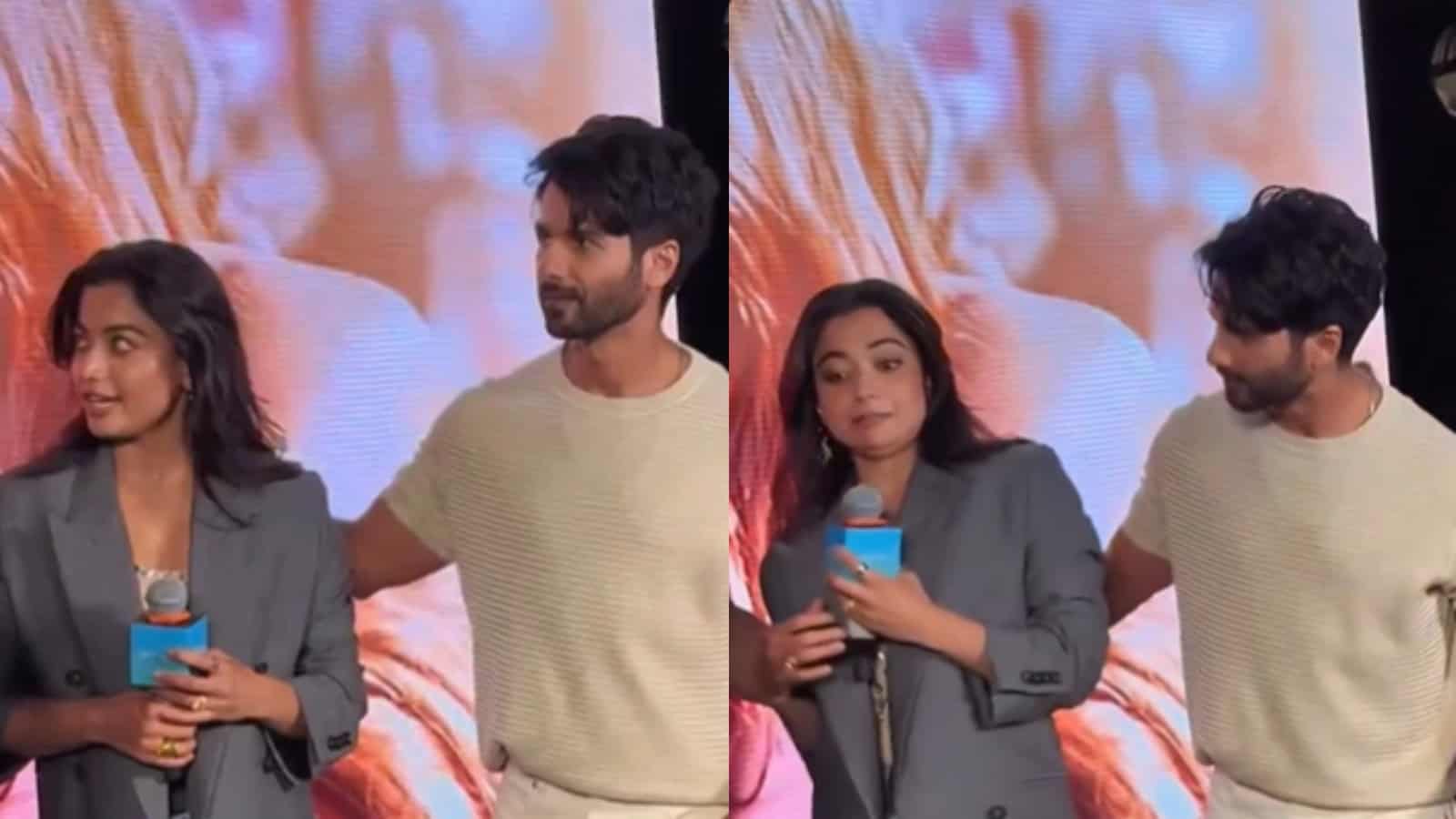 A woman and a man on stage during a media event, with a large screen displaying an image in the backgroun.