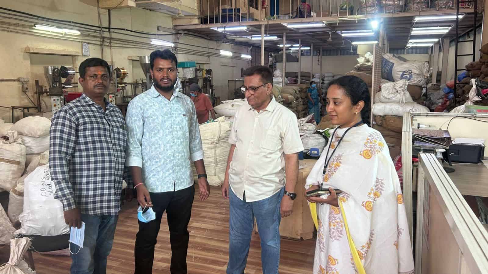 Manufacturing workers inspecting textiles in a busy factory setting, with fabric rolls and machinery in t.