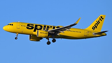 Yellow Spirit Airlines plane flying with the company logo visible on the fuselage and tail.