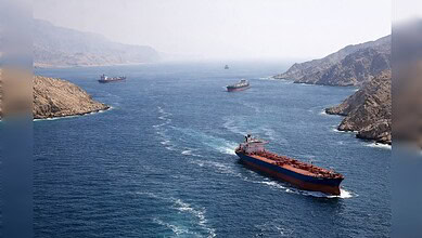 Oil tankers navigating a waterway between rugged coastal hills.