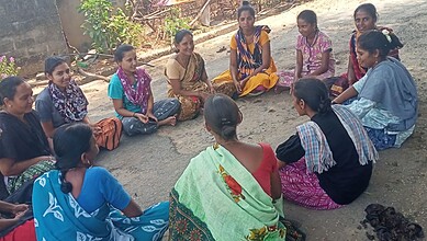 Group of adolescent girls and women participating in a community development session outdoors in Telangan.