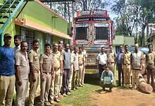 Truck convoy with personnel and logs in a rural setting, India.