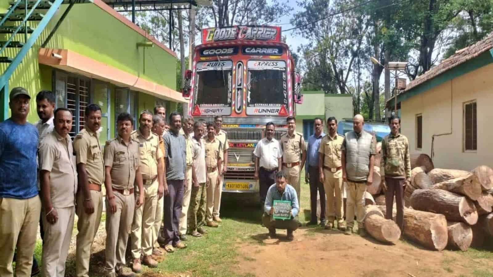 Truck convoy with personnel and logs in a rural setting, India.