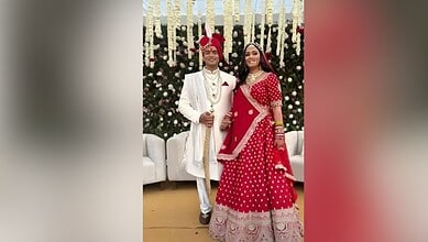 A young couple dressed in traditional Indian wedding attire at a festive celebration.