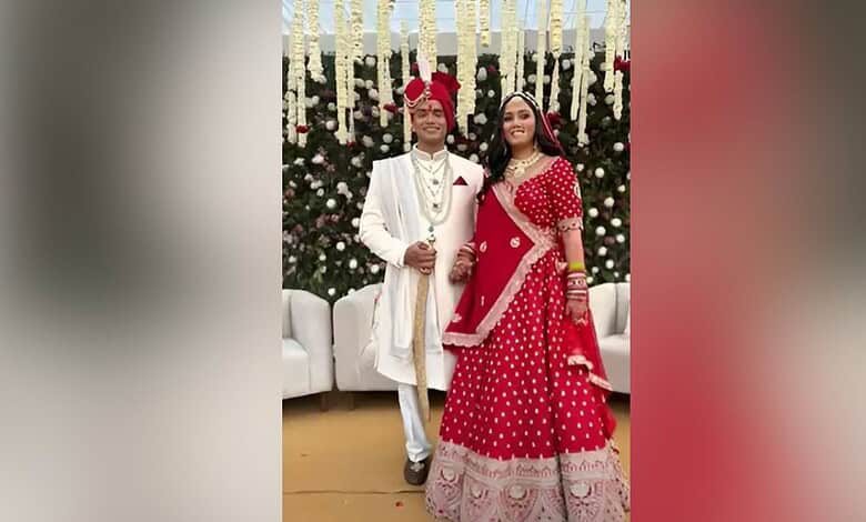 A young couple dressed in traditional Indian wedding attire at a festive celebration.
