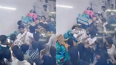 A crowded scene at an indoor event with people engaged in a physical altercation or scuffle.