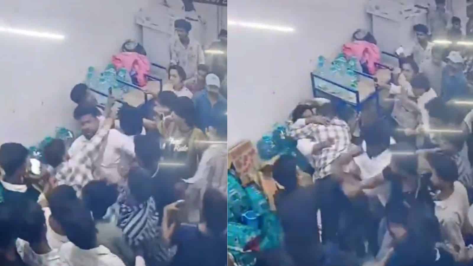 A crowded scene at an indoor event with people engaged in a physical altercation or scuffle.