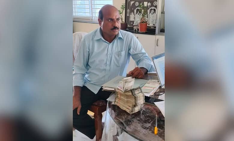 Man with a mustache sitting at a desk with stacks of cash and a laptop in an office.
